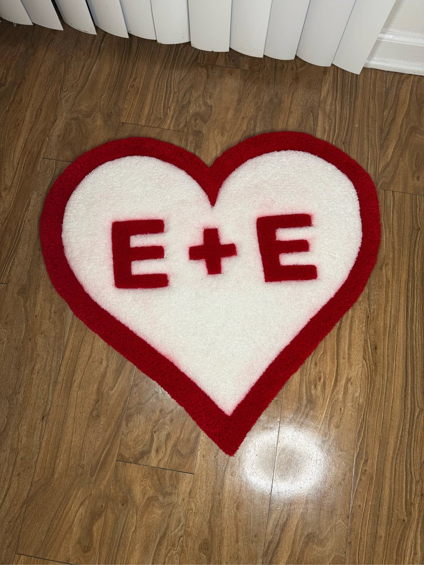 Large Valentines Heart custom tufted premium rug with custom initials laying on wood floor - top view