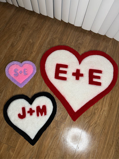 All sizes of Valentines Heart custom tufted premium rugs with custom initials laying on wood floor - top view
